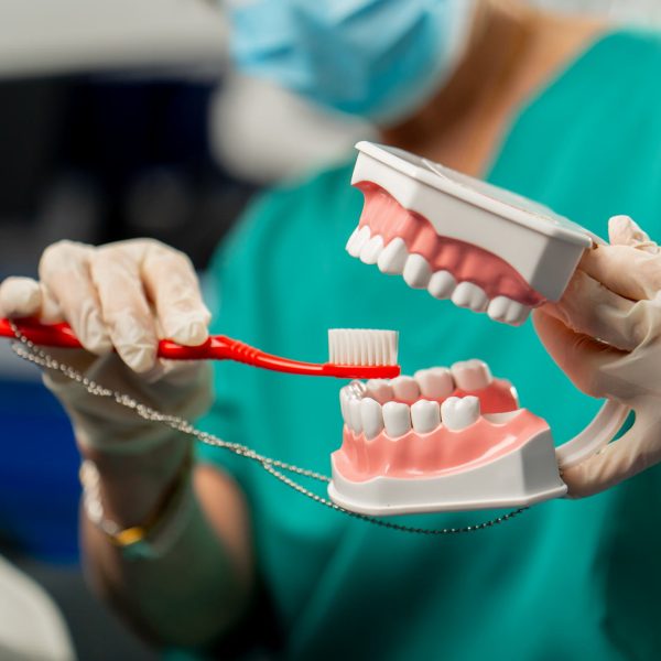 close up in a dental clinic a dentist shows a patient how to brush his teeth correctly